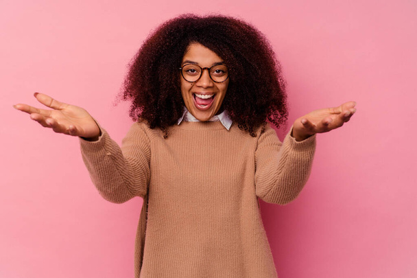 Young african american woman isolated on pink background feels confident giving a hug to the camera. - Photo, Image