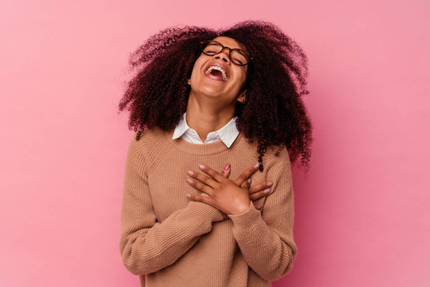 ピンクを背景に孤立した若いアフリカ系アメリカ人女性が手を取り合って笑い、幸せの概念. - 写真・画像