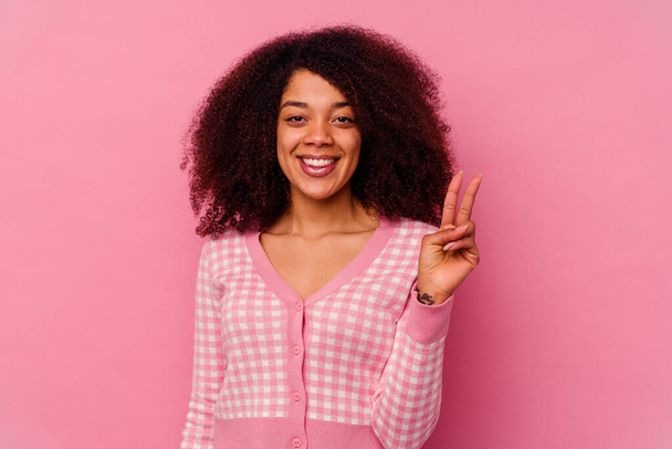 Giovane donna afroamericana isolato su sfondo rosa mostrando segno di vittoria e sorridente ampiamente. - Foto, immagini