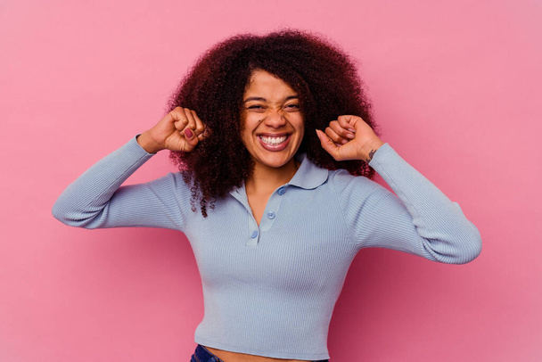 Fiatal afro-amerikai nő elszigetelt rózsaszín háttérrel ünnepli a győzelem, a szenvedély és a lelkesedés, boldog kifejezés. - Fotó, kép