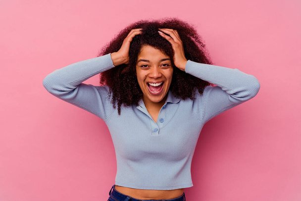 Young african american woman isolated on pink background screaming, very excited, passionate, satisfied with something. - 写真・画像