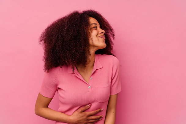 Nuori afrikkalainen amerikkalainen nainen eristetty vaaleanpunainen tausta koskettaa vatsa, hymyilee varovasti, syöminen ja tyytyväisyys käsite. - Valokuva, kuva