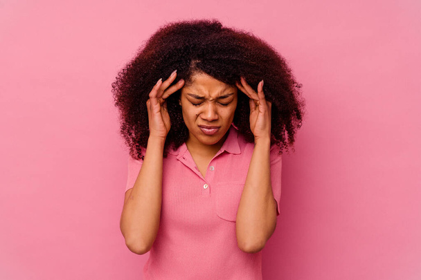 Junge Afroamerikanerin isoliert auf rosa Hintergrund berührt Schläfen und hat Kopfschmerzen. - Foto, Bild