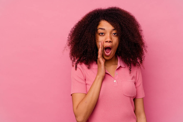 Junge afrikanisch-amerikanische Frau isoliert auf rosa Hintergrund schreit laut, hält Augen offen und Hände angespannt. - Foto, Bild