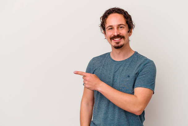 Young caucasian man isolated on white background smiling and pointing aside, showing something at blank space. - Photo, Image