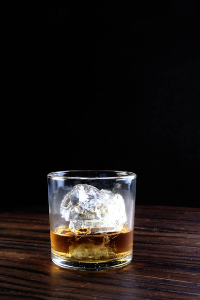shot of whiskey served in a short glass with ice isolated on black background. - Foto, Imagem