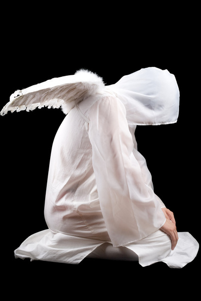 Sitting man dressed in angel suit. Isolated on black - Photo, Image