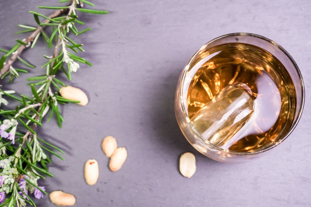 sklenice whisky s vlašskými ořechy a rozmarýnovou květinou na kamenném podnosu, pohled shora - Fotografie, Obrázek