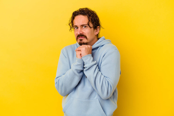 Young caucasian man isolated on yellow background scared and afraid. - Photo, Image