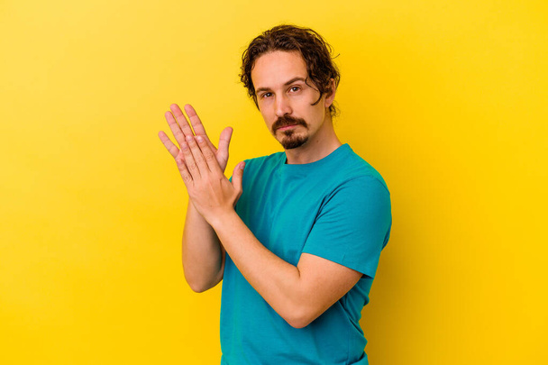 Young caucasian man isolated on yellow background feeling energetic and comfortable, rubbing hands confident. - Photo, Image