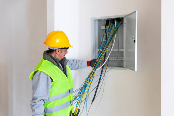 The electrician looking at the electrical panel. - Photo, Image