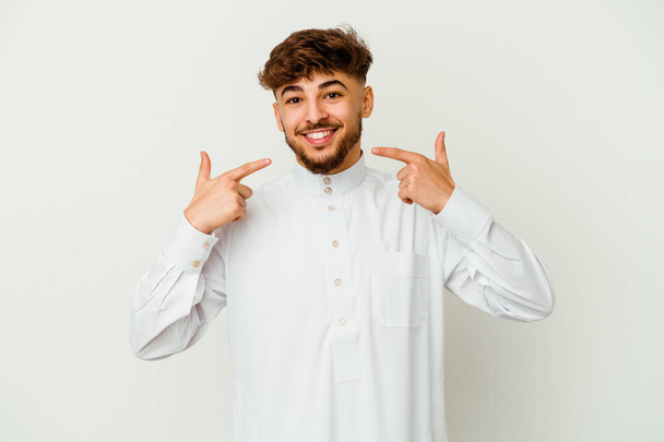 Giovane marocchino indossa un tipico abiti arabi isolati su sfondo bianco sorride, puntando il dito verso la bocca. - Foto, immagini