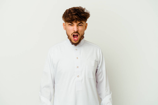 Młody Marokańczyk w typowym arabskim ubraniu odizolowany na białym tle krzyczy bardzo wściekły i agresywny. - Zdjęcie, obraz