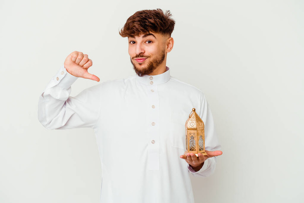 Junger marokkanischer Mann in typischer arabischer Kleidung, der eine Ramadan-Lampe auf weißem Hintergrund hält, fühlt sich stolz und selbstbewusst, Vorbild zu sein. - Foto, Bild
