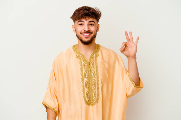 Junge marokkanische Mann isoliert auf weißem Hintergrund fröhlich und zuversichtlich zeigt ok Geste. - Foto, Bild