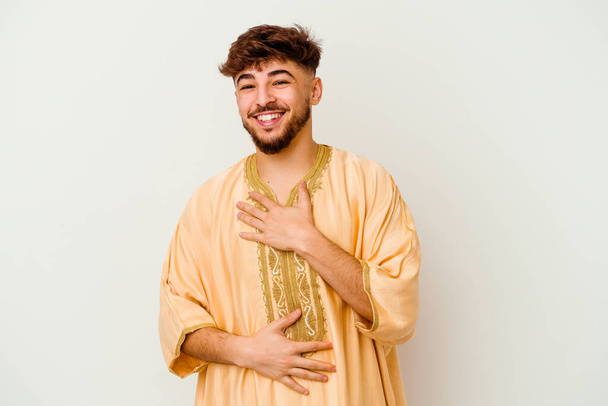 Fiatal marokkói férfi elszigetelt fehér háttér nevet boldogan, és szórakoztató tartja a kezét a gyomorban. - Fotó, kép