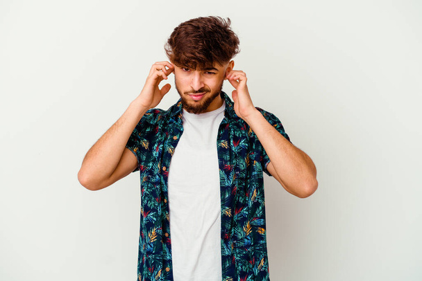 Junger marokkanischer Mann isoliert auf weißem Hintergrund, der die Ohren mit Fingern bedeckt, gestresst und verzweifelt durch eine laute Umgebung. - Foto, Bild