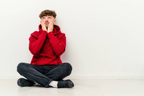 Young Moroccan man sitting on the floor isolated on white background whining and crying disconsolately. - Photo, Image