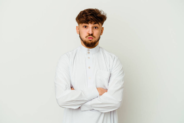 白い背景に隔離された典型的なアラブ服を身に着けている若いモロッコ人は頬を吹いて、疲れた表情をしています。表情コンセプト. - 写真・画像