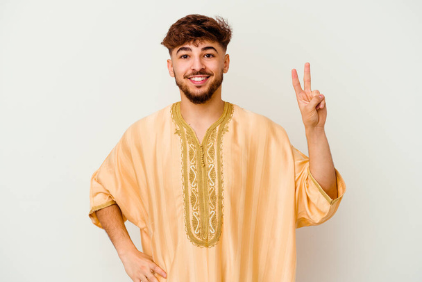 Nuori marokkolainen mies eristyksissä valkoisella taustalla iloinen ja huoleton osoittaa rauhan symboli sormin. - Valokuva, kuva
