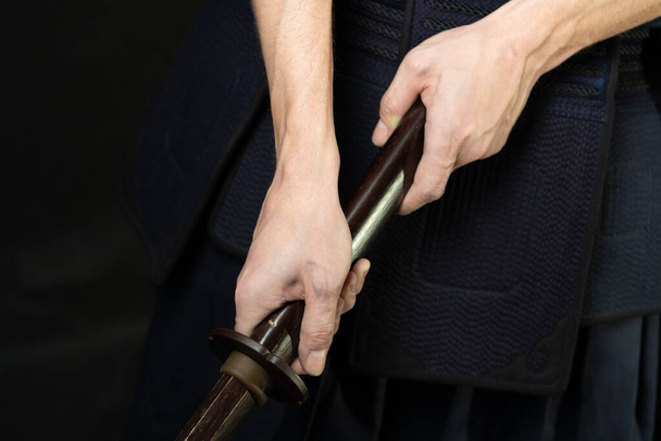 Hands with a wooden sword. Swordsman in uniform. Man kendo fighter - Foto, afbeelding