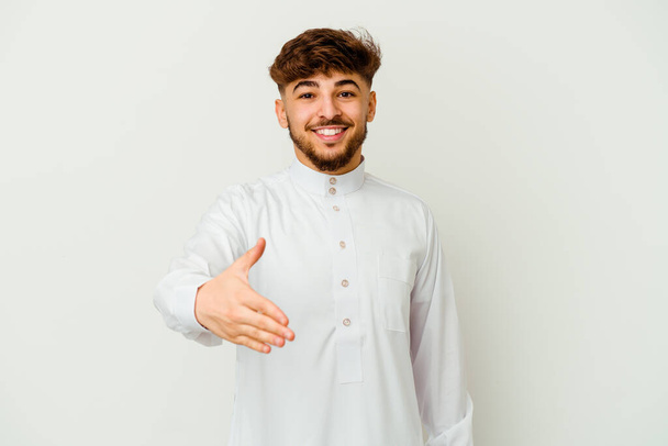 Beyaz arka planda izole edilmiş tipik bir Arap kıyafeti giyen genç Faslı adam selamlama jesti olarak kameraya uzanıyor.. - Fotoğraf, Görsel