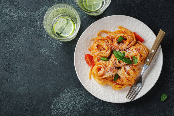 Lezzetli iştah açıcı klasik İtalyan tagliatelle makarnası domates soslu, peynirli parmesan peyniri ve siyah tabakta fesleğen. Yukarıdan bak, yatay. Kopyalama alanı olan üst görünüm - Fotoğraf, Görsel