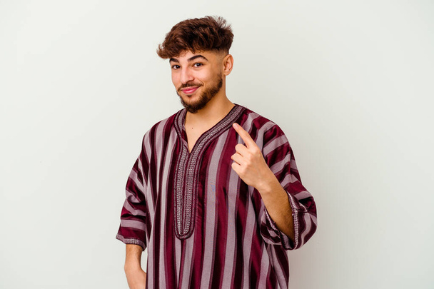 Mladý Maročan izolovaný na bílém pozadí ukazuje prstem na vás, jako by pozvání přijít blíž. - Fotografie, Obrázek