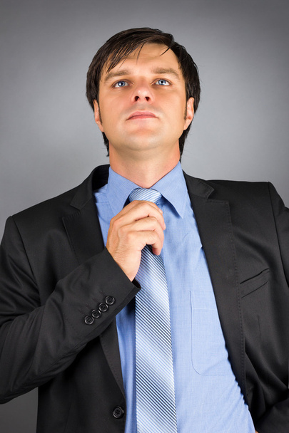 Portrait of a young businessman adjusting his neck tie getting r - Foto, afbeelding