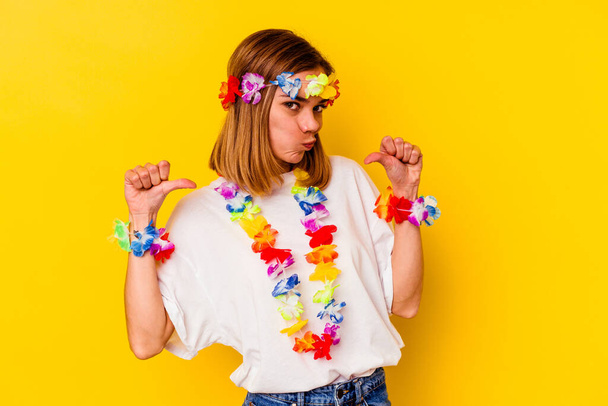 Mladá běloška oslavující havajskou párty izolovanou na žlutém pozadí se cítí hrdá a sebevědomá, příklad následování. - Fotografie, Obrázek