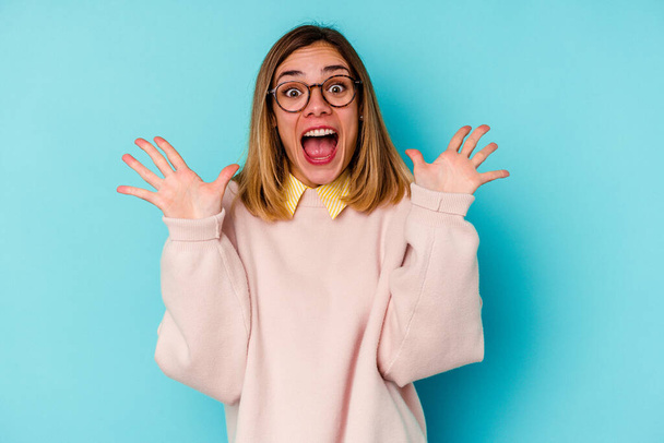 Young student caucasian woman isolated on blue background celebrating a victory or success, he is surprised and shocked. - Photo, Image