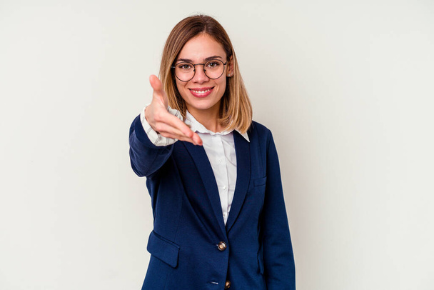 Jeune femme caucasienne d'affaires isolée sur fond blanc étirant la main à la caméra en geste de salutation. - Photo, image