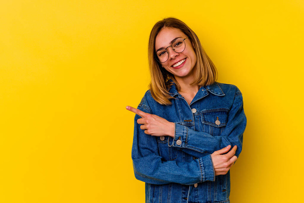 Young caucasian skinny woman isolated on yellow background smiling cheerfully pointing with forefinger away. - 写真・画像