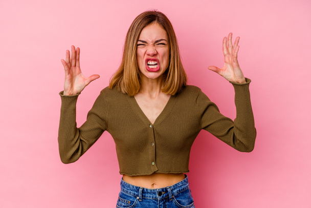 Молодая белая женщина, изолированная на розовом фоне, кричащая от ярости. - Фото, изображение