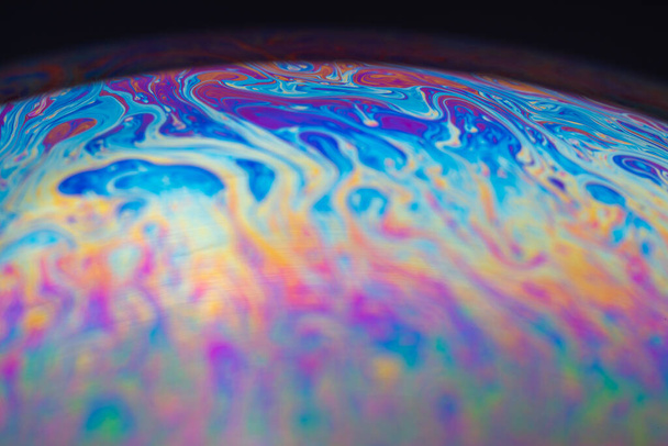 Soap bubble iridescent colors close-up on the surface of the iridescent spots. Round sphere planet-like abstraction. - Photo, Image