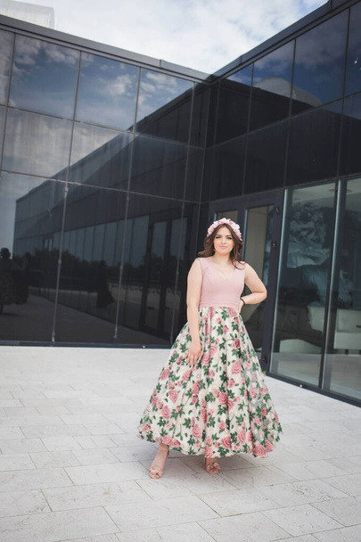 A vertical shot of a woman in front of a modern building in a pink dress - Foto, immagini