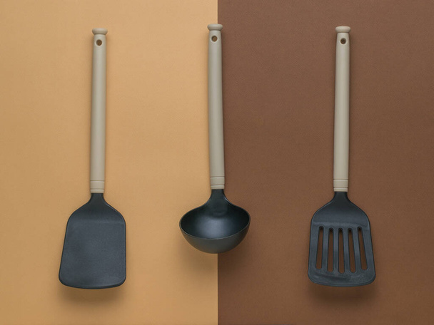 Two kitchen spatulas and a ladle on a two-color background. Plastic kitchen tools. Flat lay. - Photo, Image