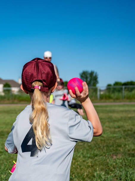 blond blank meisje met een hoed gooien van een honkbal - Foto, afbeelding