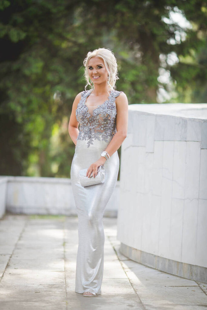 A shallow focus vertical shot of a young woman posing near a wall in a silver dress - Фото, зображення