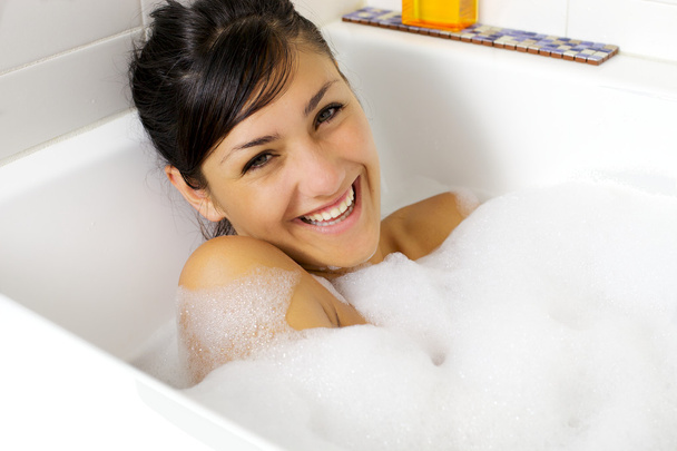 Smiling beautiful young woman in bathtub full of foam - Foto, immagini