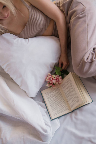 Morning girls: blonde in sitting on the bed. waking up from a dream. I just woke up. a girl is reading a book - Photo, image