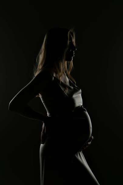 silhouette of Pregnant woman on a black background - Foto, afbeelding