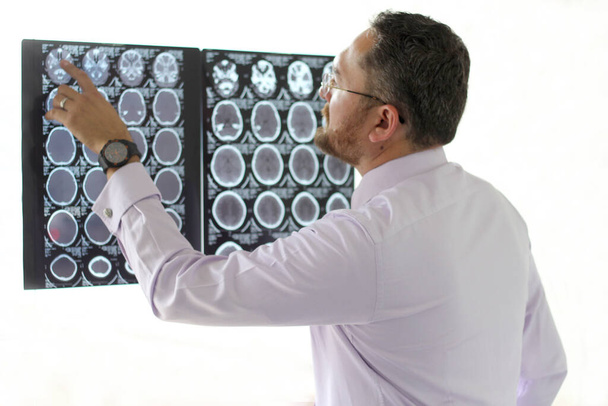 Γιατρός Ιατρός Ειδικός στην Επαγγελματική Νευρολογία της εργασίας του εξετάζει ακτινογραφίες του εγκεφάλου ή αξονική τομογραφία του ασθενούς του - Φωτογραφία, εικόνα