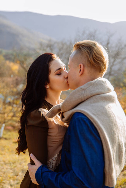 Young couple kissing on the background of forest and mountains - 写真・画像