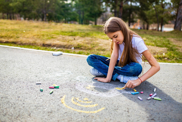 Little girl with creative craft hobby drawing electro on the asphalt with chalk car environment, eco friendly, save energy in park at summer day - Fotografie, Obrázek