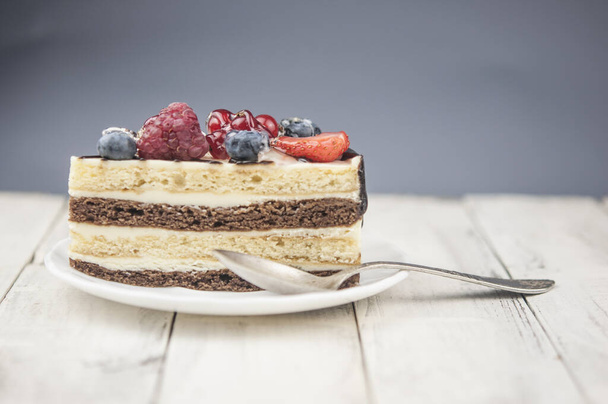 Змішайте торт зі шматочками ягід на білій тарілці на фоні дерева
 - Фото, зображення