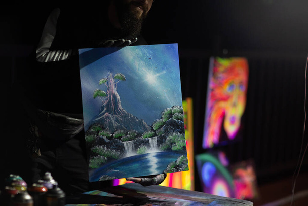 Młody uliczny artysta kończący dzieło farbą w sprayu i ogniem w ciemną noc - Zdjęcie, obraz