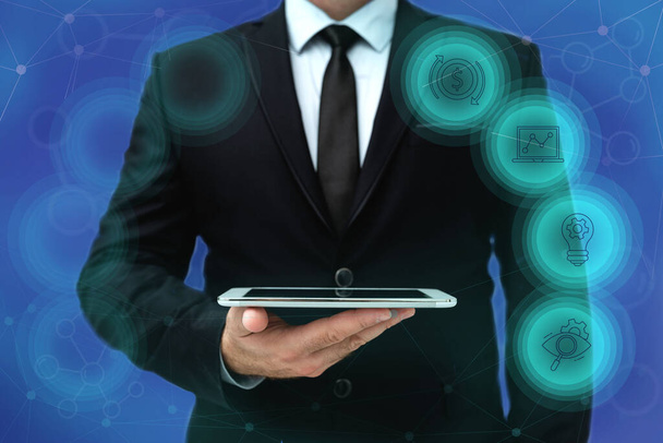 Man In Office Uniform Standing Holding Tablet Displaying New Modern Technology. Gentleman In Business Attire Carrying Tab Pointing New Futuristic Technology. - Photo, Image