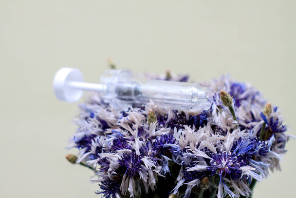 syringe in flowers. Cosmetological procedures. Injections, injections. Diseases, treatment, medicine, vaccine. - Φωτογραφία, εικόνα