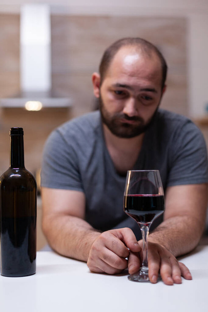 Close-up van glas met wijn voor eenzame man in de keuken - Foto, afbeelding